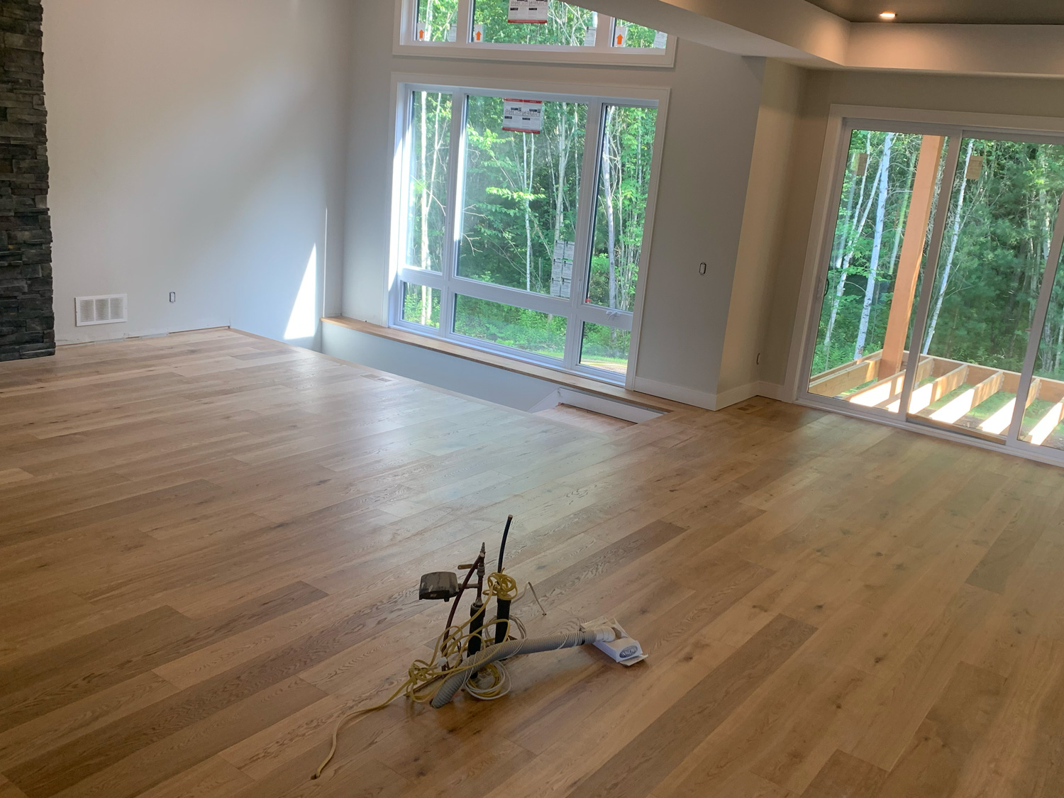Light wide-plank hardwood flooring installed across a bright open residential room