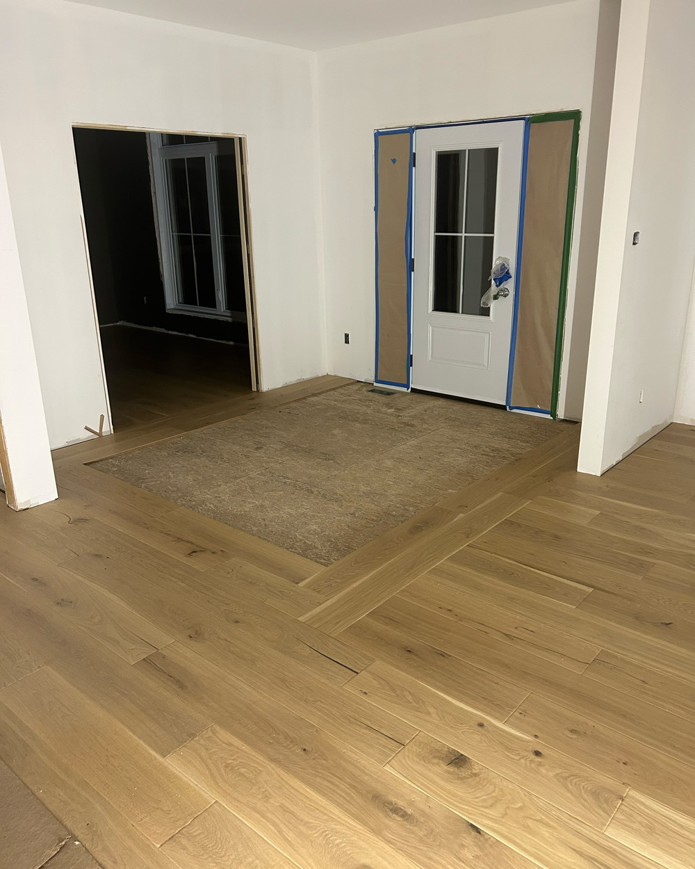 Wide-plank hardwood installation with a custom framed entry inset