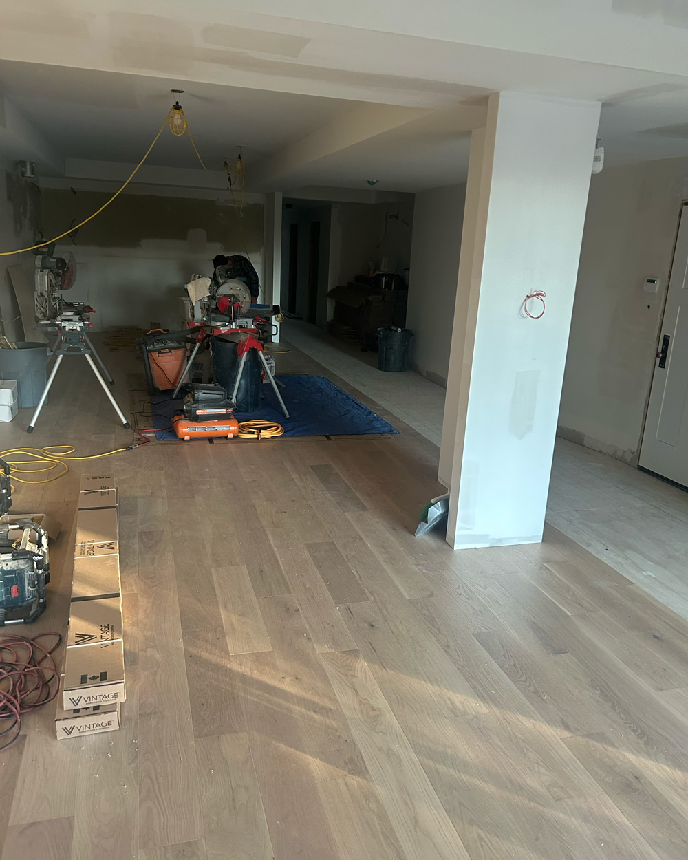 Wide-plank hardwood installation progressing through a large open-plan interior