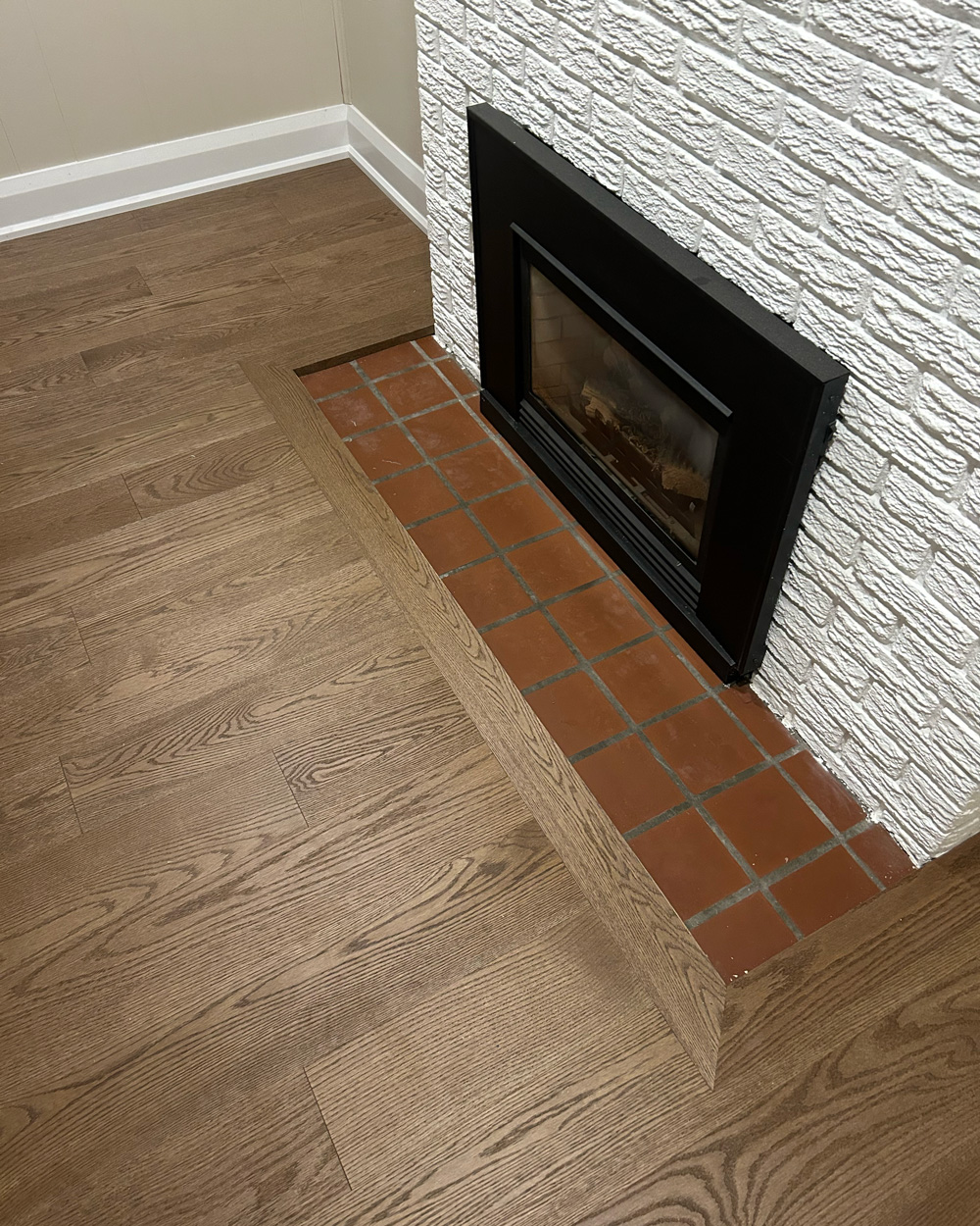 Hardwood flooring and custom border precisely fitted around a brick fireplace hearth