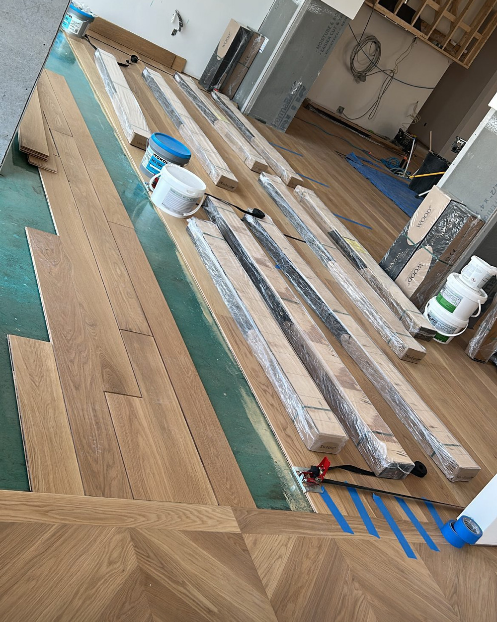 Natural hardwood installation in progress with planks staged across the work area