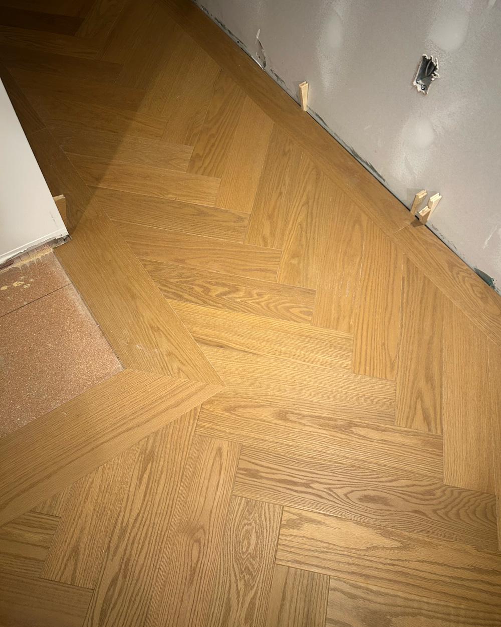Natural oak herringbone flooring with a precisely fitted perimeter border
