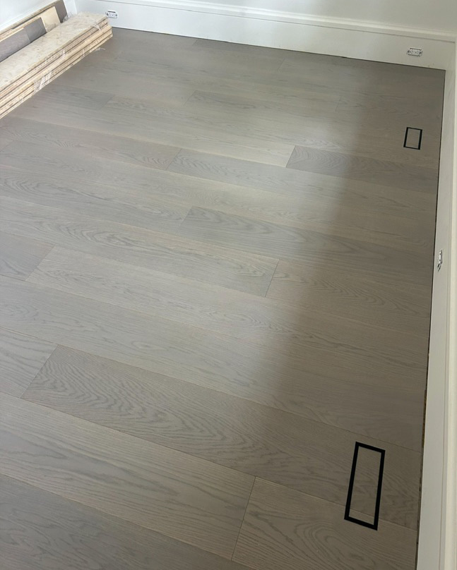 Hardwood floor installation showing clean alignment around flush vents